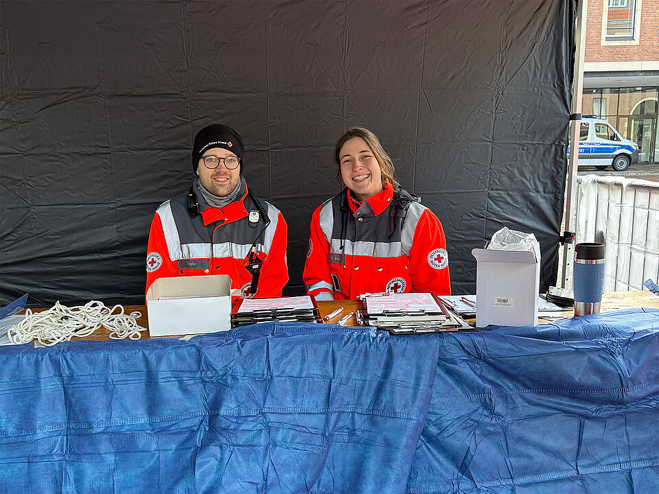 Ein Sanitäter und eine Sanitäterin sitzen am Tisch der Registrierung der Unfallhilfsstelle