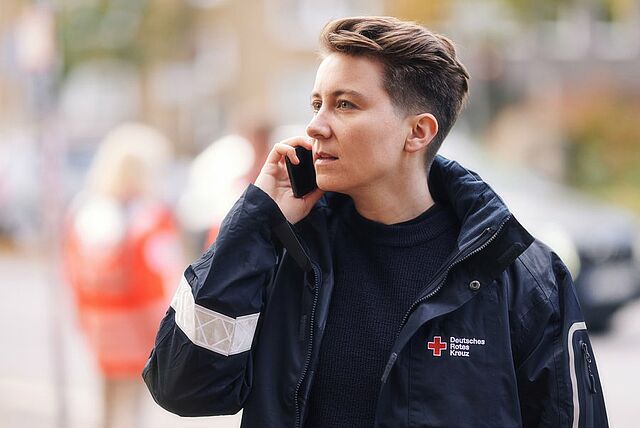 Eine Person in DRK-Kleidung am Telefon