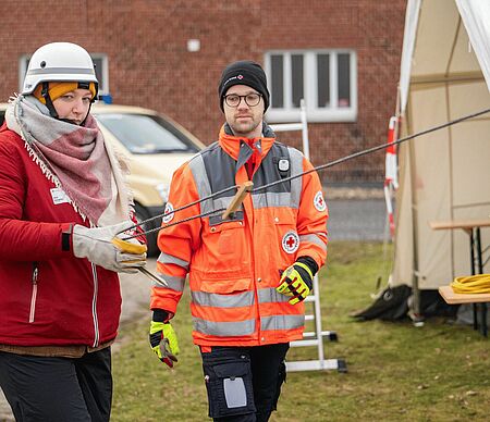  Zwei Personen, eine davon in Einsatzbekleidung beim Zeltaufbau