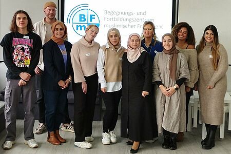 Gruppenbild mit 10 Personen vor einem Bildschirm mit dem Logo des Begegnungs- und Forschungszentrum muslimischer Frauen e.V.