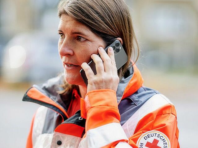Eine Person in DRK-Einsatzkleidung am Telefon