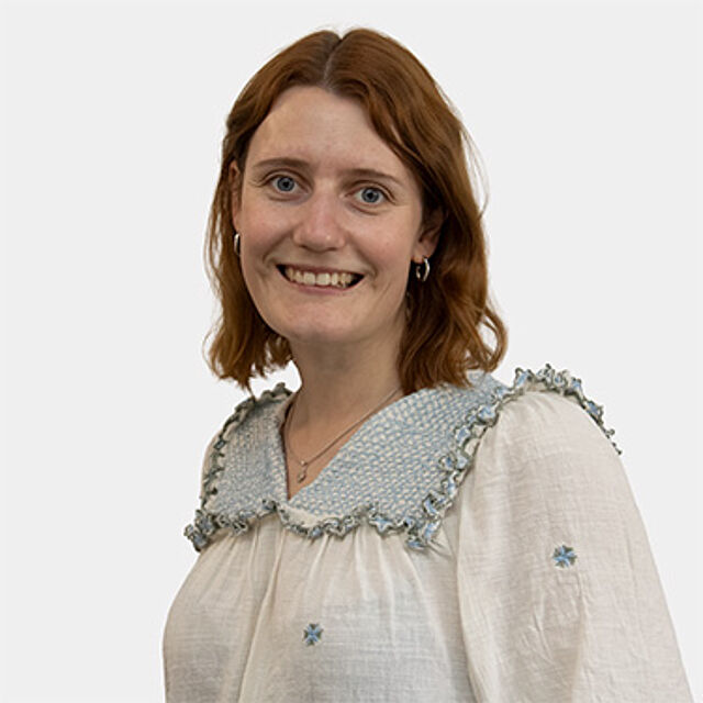Eine Frau mit mittellangen Haaren in einer weiß-blauen Bluse