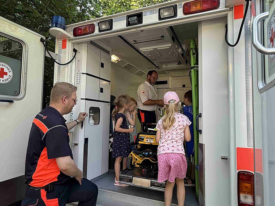 Vier Kinder und zwei Einsatzkräfte in einem DRK-Krankenwagen