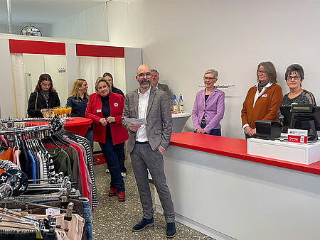 Ein Mann mit Brille in einem karierten Anzug begrüßt die Gäste