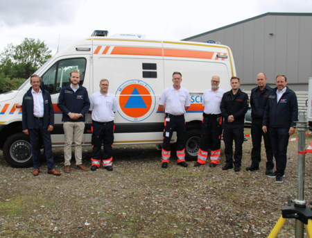 Acht Personen stehen vor einem Einsatzfahrzeug, auf dem "Medizinische Task Force" steht.