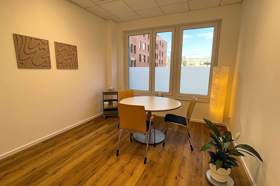 Ein Raum mit Fenster, einem runden Tisch und 3 Stühlen.