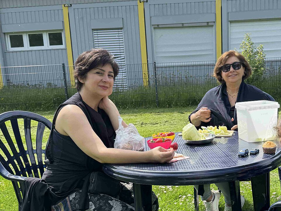 Coerde Garden Schnibbeln Zwei Personen, die an einem Tisch sitzen und Gemüse schneiden