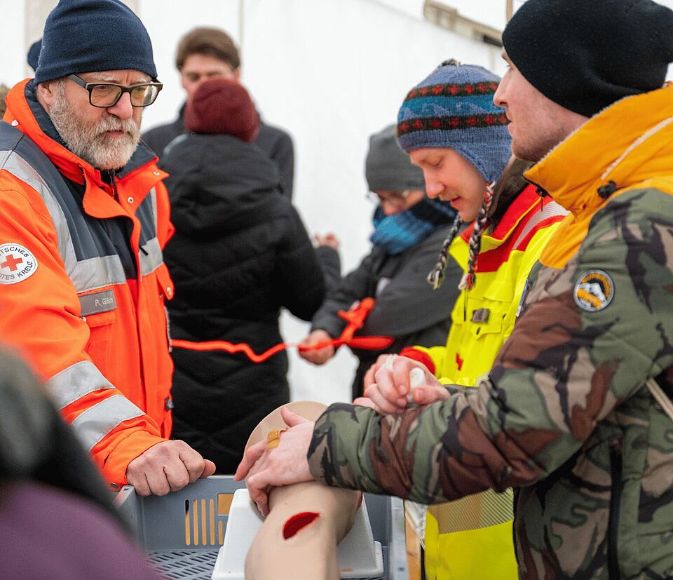 Drei Personen üben an einer Puppe den Druckverband