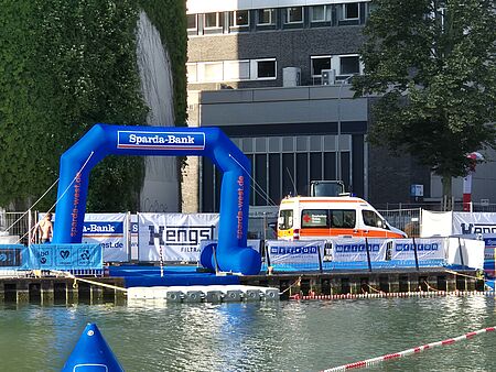 Schwimmausstieg des Triathlons am Hafen mit blauem Sparda-Bank Luftbogen und KTW im Hintergrund