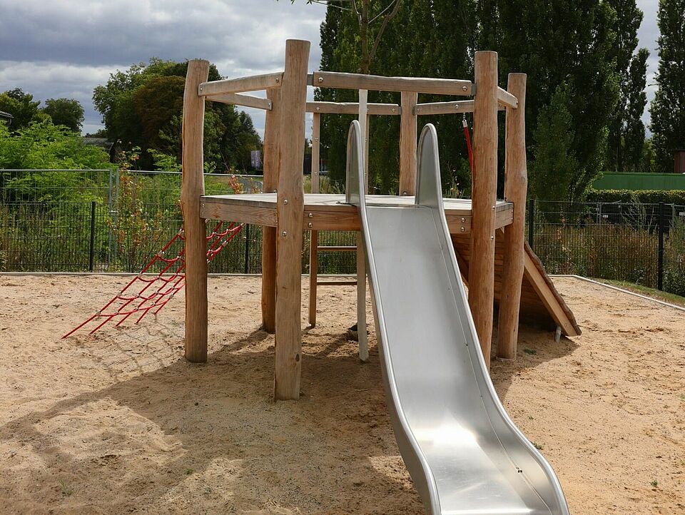 Ein Klettergerüst mit einer Rutsche in einem Sandkasten