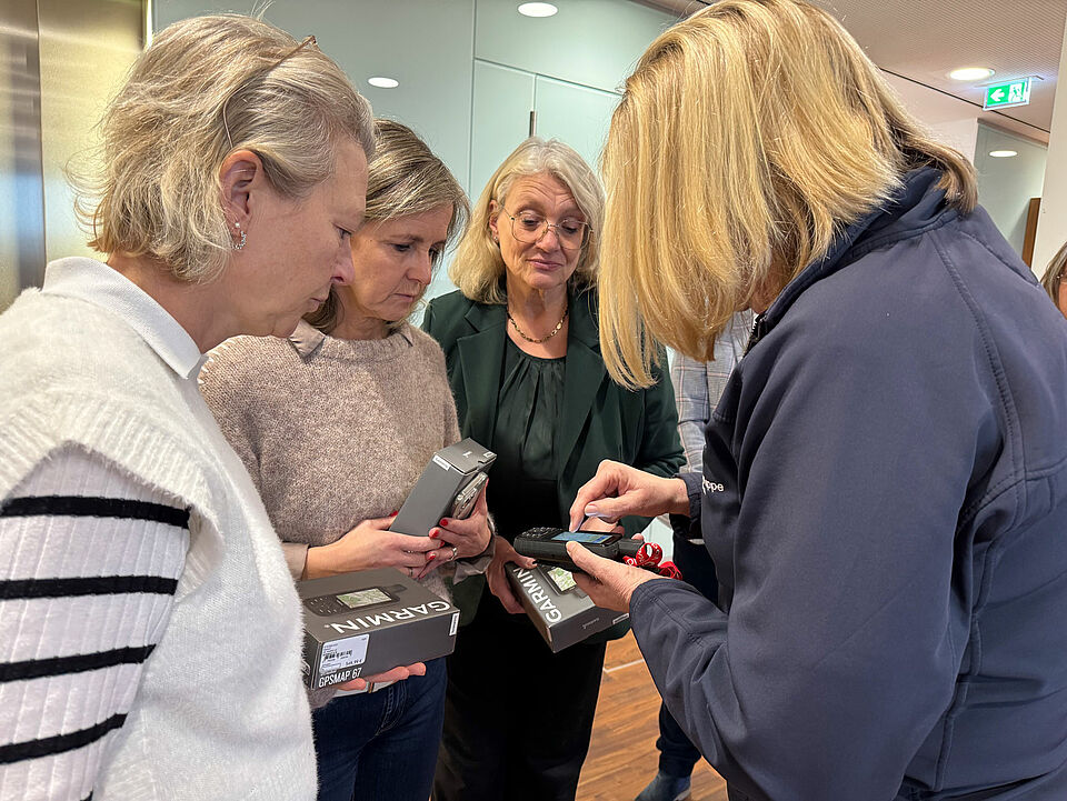 Vier Frauen stehen im Halbkreis, in ihrer Mitte ein GPS-Gerät
