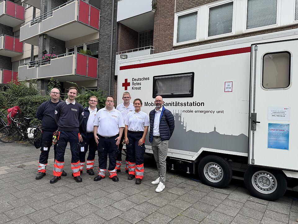 Gruppenbild von sieben Personen in Einsatzkleidung vor der mobilen Sanitätsstation