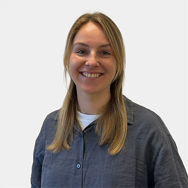 Frau mit grauer Bluse und dunkelblonden Haaren