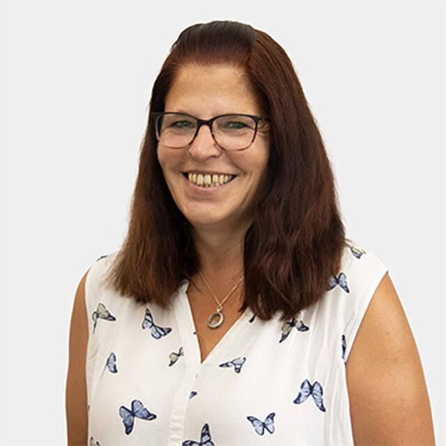 Eine Frau mit langen brauen Haaren und Brille