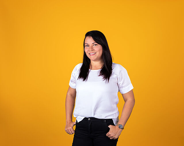 Junge Frau mit dunklen Haaren vor gelbem Hintergrund