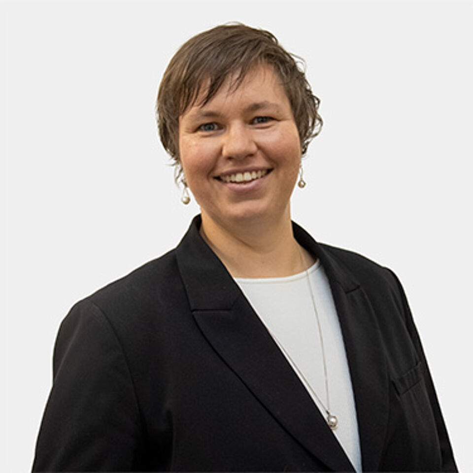 Eine Frau mit kurzen Haaren, schwarzem Blazer und weißem Shirt