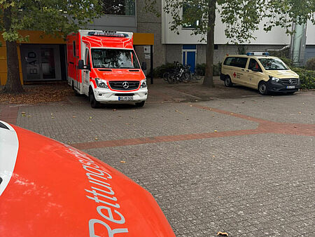 Drei Einsatzfahrzeuge vor einem Gebäude mit herbstlichen Bäumen davor
