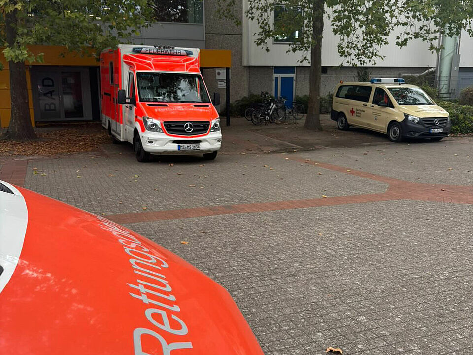 Drei Einsatzfahrzeuge vor einem Gebäude mit herbstlichen Bäumen davor