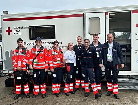 Gruppenbild mit acht Personen in Einsatzkleidung vor der Unfallhilfsstation