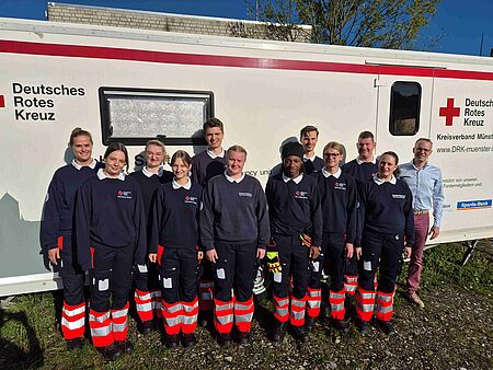 12 Personen in DRK-Einsatzkleidung vor einer Unfallhilfsstation