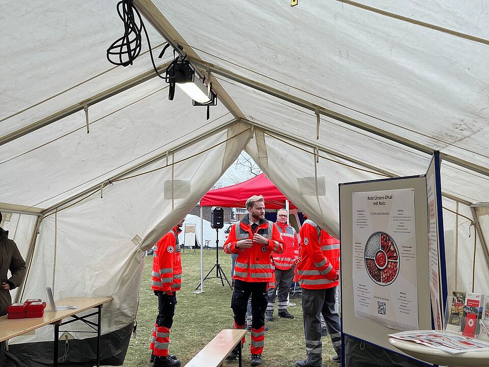 Ehrenamtliche in Einsatzkleidung stehen im Zelt der Essensausgabe