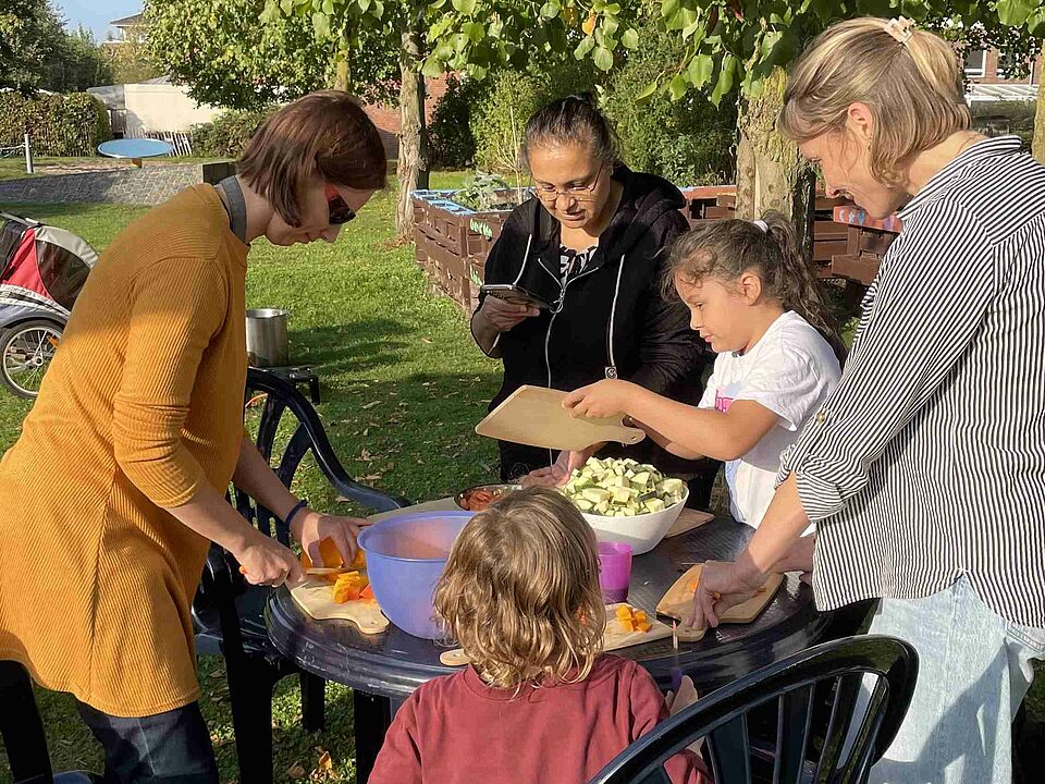 Mehrere Personen stehen um einen Tisch herum und schneiden Gemüse