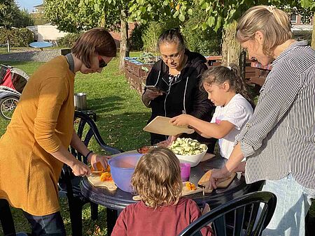 Herbstfest Mehrere Personen stehen um einen Tisch herum und schneiden Gemüse