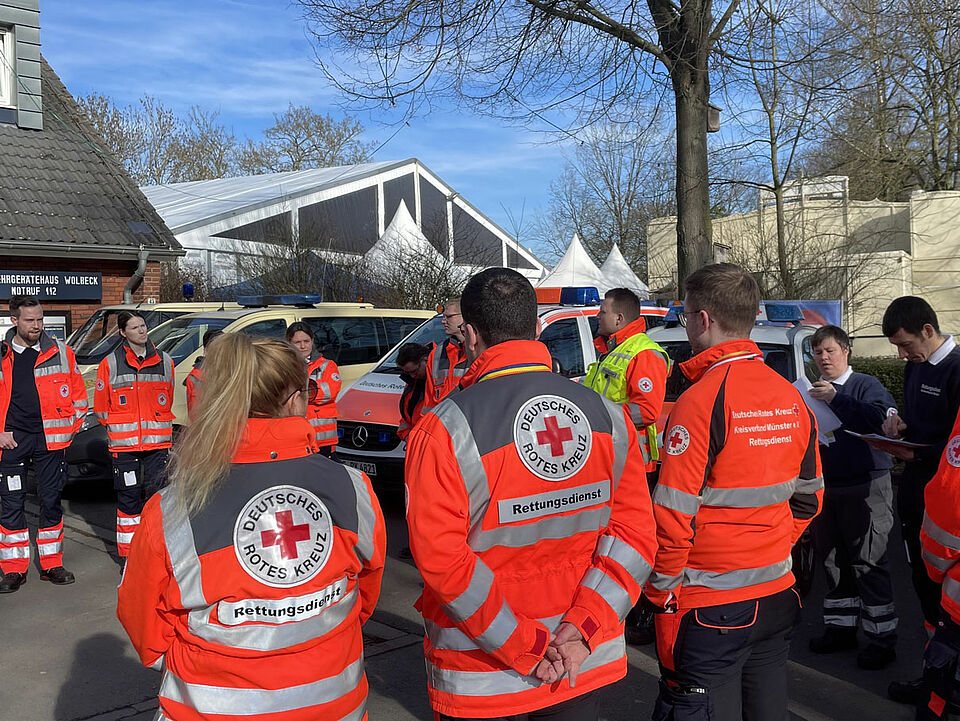 Personen in Einsatzjacke vom roten Kreuz, im Hintergrund sind die Spitzen des Festzeltes zu sehen
